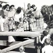 A baby show (ages 1 to 3) at the 1941 Field Day. Identified children are Bobby Osceola, Johnny Buck, Onnie Shore (Gopher), Fred Smith, and Sally Tommie. The identified women are Alice Huff Osceola, Lena Gopher, Leona Micco Smith, Annie Pearce Bowers, and Lucy Tiger.