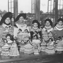  Cody Micco, Leona Micco Smith, Alice Micco, unidentified woman, and Rosalie Micco standing behind a table of dolls during a Field Day on the Brighton Reservation.