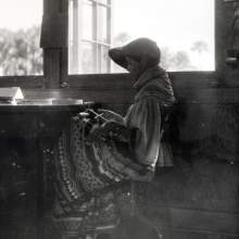  Cody Micco doing beadwork next to a window, most likely inside the school building.