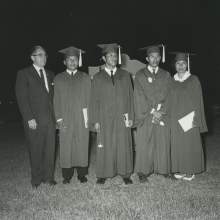  William D. Boehmer standing with Seminole graduates of Okeechobee High School in Okeechobee, Florida in their graduation caps and gowns. From left to right are William D. Boehmer, Richard Smith, Billy Micco, Brown Shore, and Gladys Bowers.